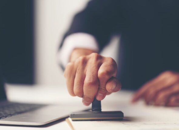 close-up-person-s-hand-stamping-with-approved-stamp-document-desk-1024x684